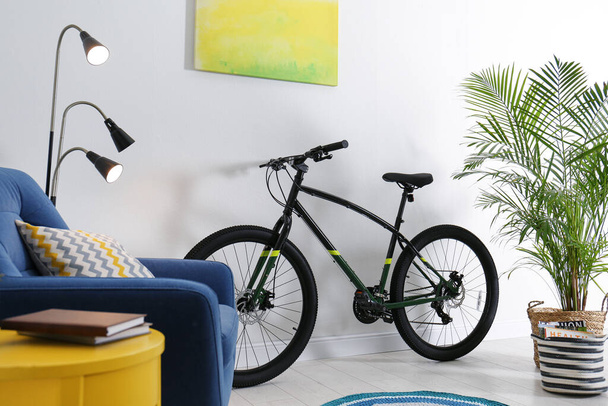 Modern bicycle and comfortable armchair in stylish living room interior - Foto, imagen