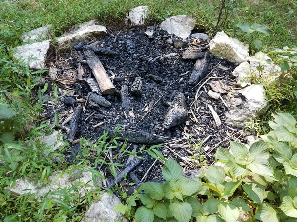 μαύρο καμένο ξύλο ή κορμοί και πέτρες σε λάκκο φωτιάς - Φωτογραφία, εικόνα