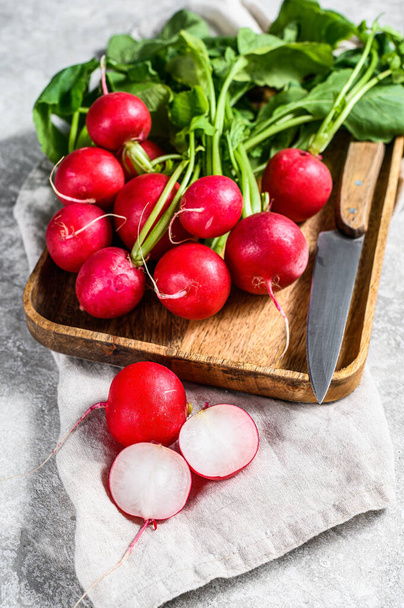 Fresh red radishes in a wooden bowl. Farm organic vegetables. Gray background. Top view. - Photo, Image