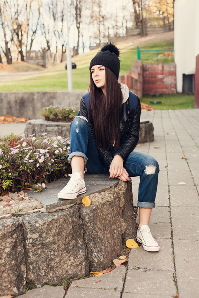 Teen girl sitting on stairs against grunge wall - Photo, image