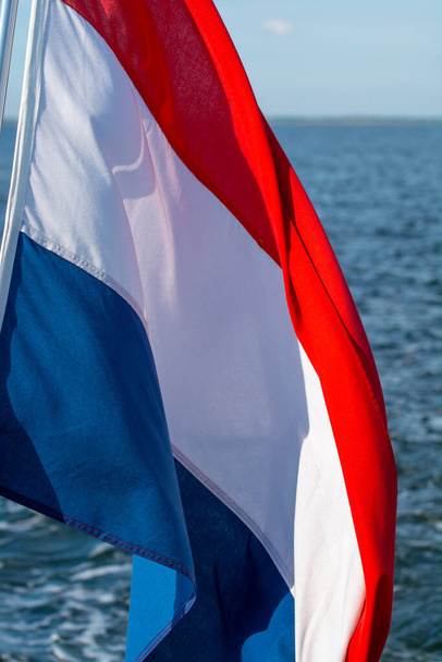 Drapeau bleu blanc rouge néerlandais sur fond d'eau de mer gros plan - Photo, image