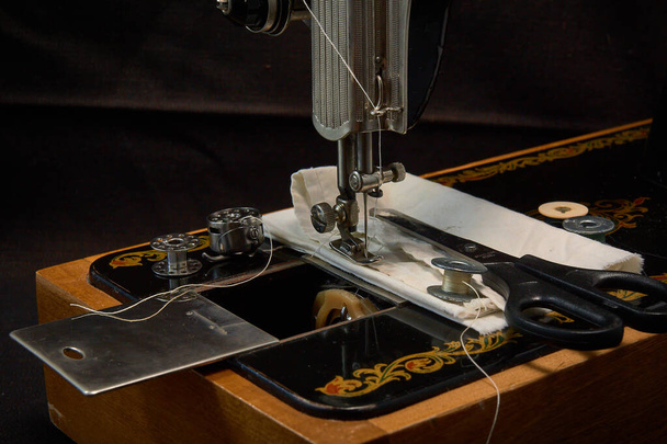 Швейная машина и детали на темном фоне
 - Фото, изображение