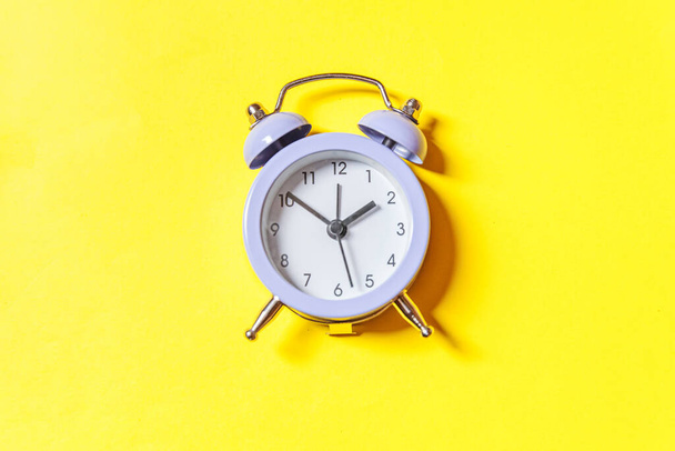 Simply minimal design ringing twin bell vintage classic alarm clock Isolated on yellow background. Rest hours time of life good morning night wake up awake concept. Flat lay top view copy space - Photo, Image