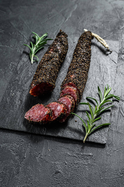 Sausage fuet. Pork sausage. Italian antipasto. Black background. Top view. - Фото, изображение