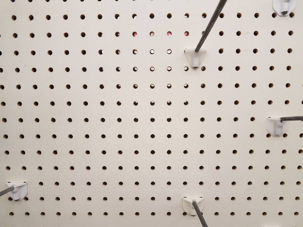 pegboard blanco vacío o pared con agujeros y ganchos o perchas de metal
 - Foto, imagen
