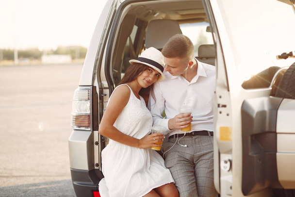 Beautiful couple spend time in a summer park near a car - Photo, image