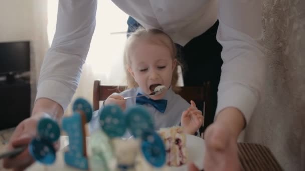 A child eats a birthday cake. Birthday celebration at home - Materiał filmowy, wideo