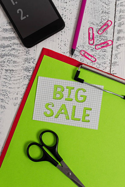 Text sign showing Big Sale. Conceptual photo massive commercial event where merchandise is sold at a reduced price Clipboard sheet pencil smartphone scissors note clips wooden background. - Zdjęcie, obraz