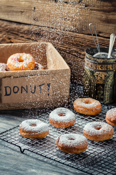 Closeup of falling powder sugar on fresh donuts - Fotoğraf, Görsel