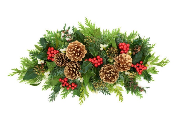 Christmas composition with gold pine cones, holly, mistletoe, ivy & cedar cypress fir leaves on white background. Xmas & New Year decorative display. Flat lay, top view, copy space. - Фото, изображение