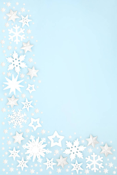 Christmas snow covered border with white star, snowflake & ball bauble decorations on pastel blue background. Xmas & winter & New Year composition for the festive holiday season.  - Photo, Image