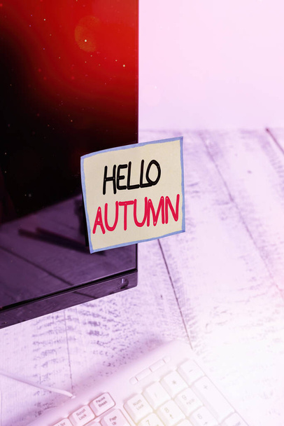 Handwriting text Hello Autumn. Concept meaning that weather begins to get colder and trees shed their leaves Notation paper taped to black computer monitor screen near white keyboard. - Photo, Image