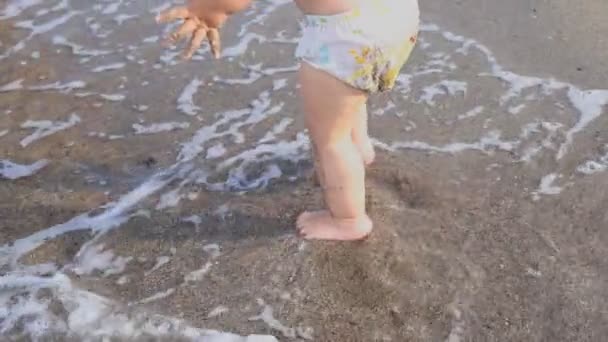 Back view cute adorable samotny mały chłopiec kaukaski maluch w szortach pływackich chodzenie przez błękitne fale czystej wody tropikalnego morza lub plaży oceanicznej. Wakacje i podróże z małymi dziećmi pojęcie - Materiał filmowy, wideo