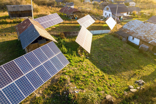 Vista aérea de cima para baixo dos painéis solares fotovoltaicos na área rural verde. Energia renovável limpa no ambiente privado da aldeia. - Foto, Imagem