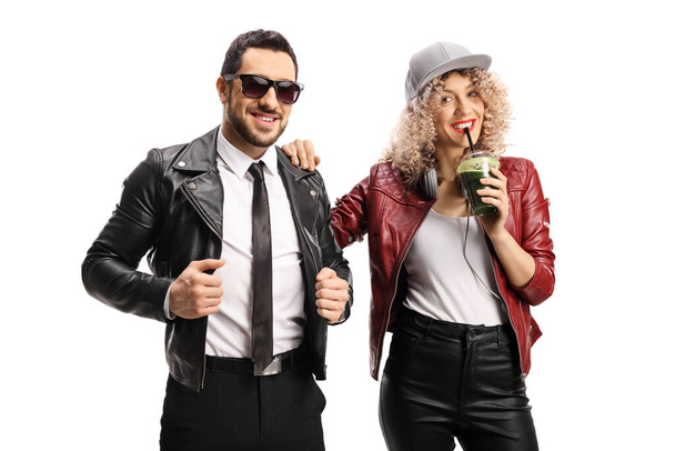 Trendy man and woman in leather jackets with a green smoothie posing isolated on white background - Fotó, kép