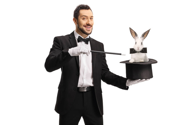 Magician pulling a rabbit from a hat with a wand isolated on white background - Photo, image