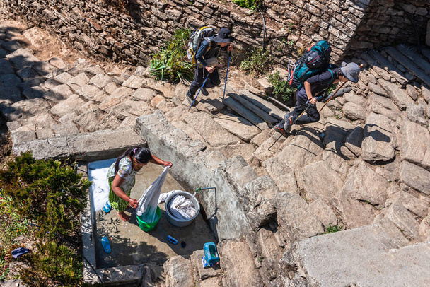 Pokhara, Nepal : Woman washing clothes and hikers in mountain village  - Φωτογραφία, εικόνα