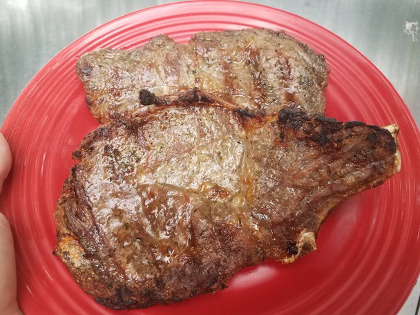 two cooked grilled steaks on a red plate - Photo, Image