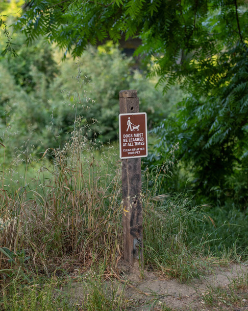 A sign at unidentified location in Englshi, saying that dogs must be on a leash and that one needs to clean after his pets- nature trail sign - Photo, Image