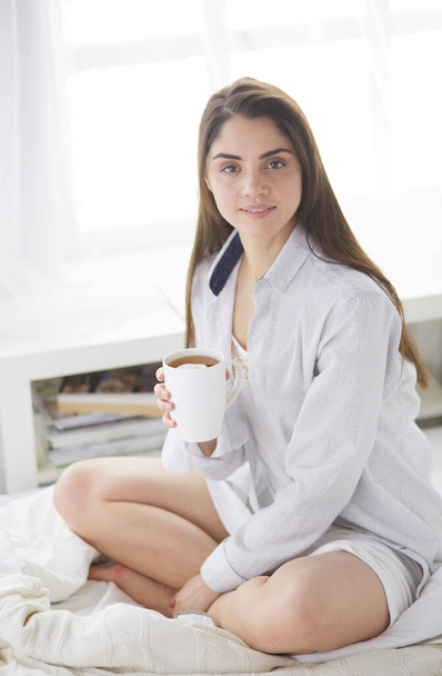 Woman sitting in bed reading a book and having breakfast - Foto, Imagem