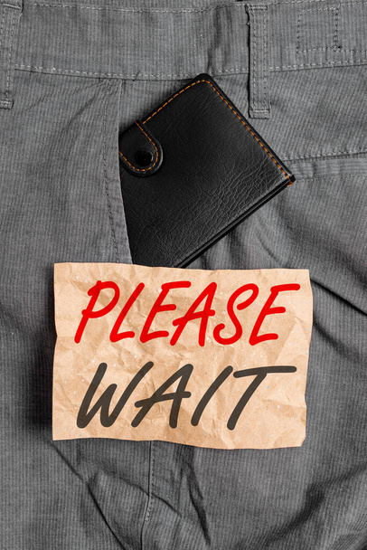 Word writing text Please Wait. Business concept for to pause any implemented action immediately and hold on Small little wallet inside man trousers front pocket near notation paper. - Photo, Image