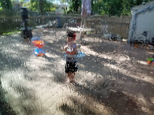 Маленький ребенок, брызгающий в окно водяным пистолетом
 - Фото, изображение