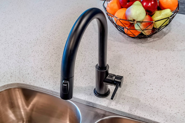 Curved gooseneck shaped black faucet over kitchen island sink with double bowls - Photo, Image