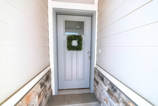 Square leafy wreath on front door entrance with glass pane and transom window - Photo, Image