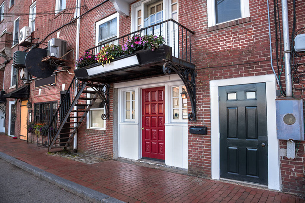 Zemin katta renkli ahşap kapıları ve birinci kata kadar harici çelik merdivenleri olan yenilenmiş eski tuğla binalar. Portsmouth, NH, ABD. - Fotoğraf, Görsel