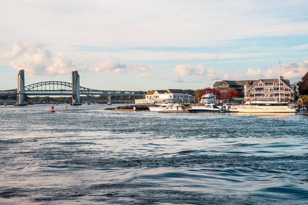 Човни пришвартовані до пристані на березі річки з мостом на задньому плані під час заходу сонця. Кіттері, я, США. - Фото, зображення