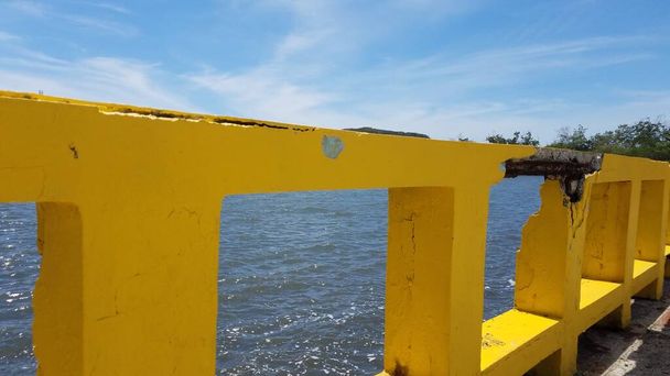 Garde-corps en ciment jaune endommagé avec barre métallique et eau de mer en Guanica, Puerto Rico - Photo, image