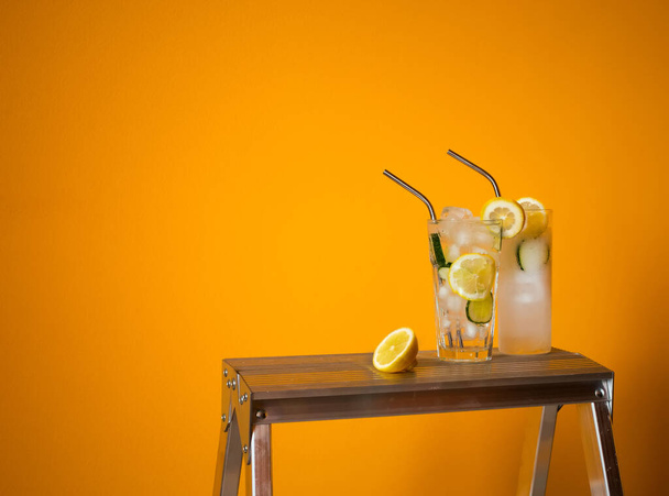 Tonico rinfrescante e gin Tom Collins cocktail o limonata con ghiaccio al limone e cetriolo su sfondo giallo a contrasto. Bar menu, alcool ricetta arredamento, sito web specializzato blog design
. - Foto, immagini