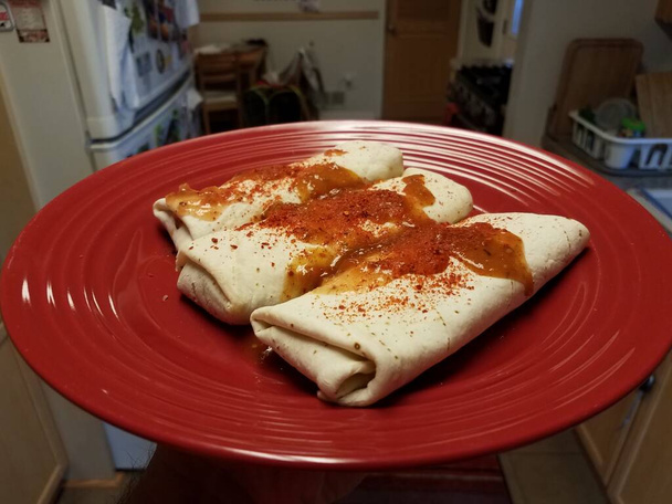 burritos na červeném talíři s červenou paprikou a pikantní salsou v kuchyni - Fotografie, Obrázek