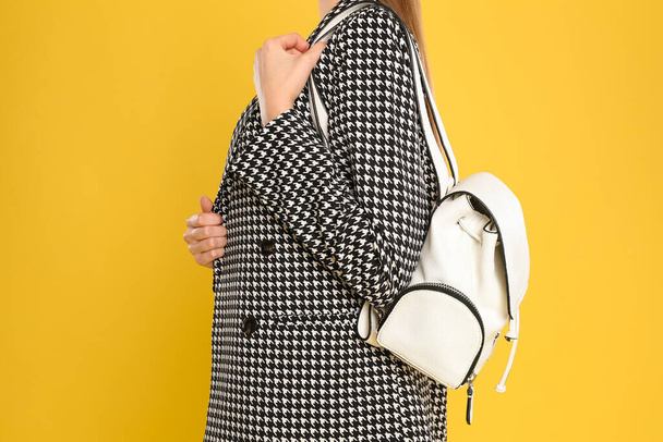 Young woman with stylish bag on yellow background, closeup - Foto, afbeelding