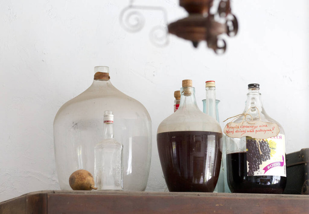 oude flessen en glas wijn op tafel - Foto, afbeelding