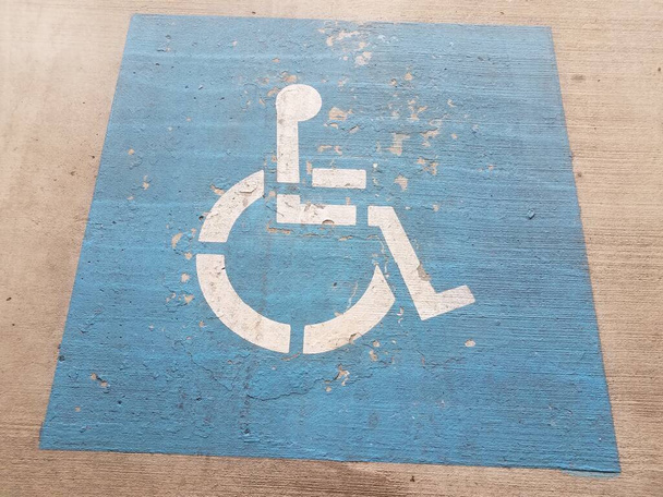 simbolo blu della sedia a rotelle o del parcheggio per disabili su cemento o pavimentazione
 - Foto, immagini