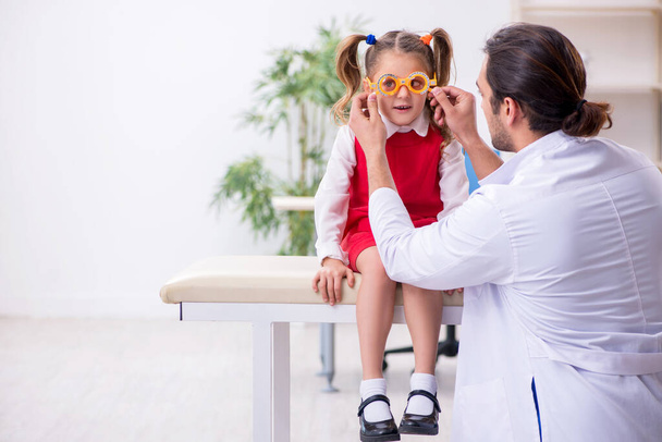 Маленькая девочка, навещающая молодого врача-окулиста - Фото, изображение