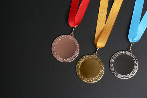 Gold, silver and bronze medals on black background, flat lay. Space for design - Zdjęcie, obraz