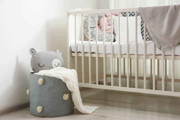 Basket with toy near crib in baby room. Interior design - Фото, зображення