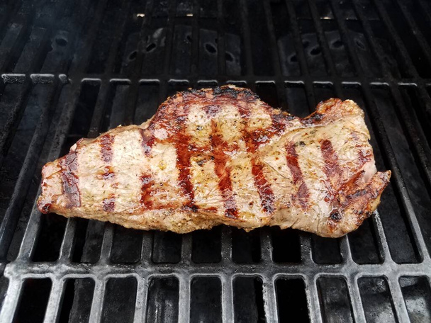 gekookt steak vlees op barbecue grill rek met vloeistof of marinade - Foto, afbeelding