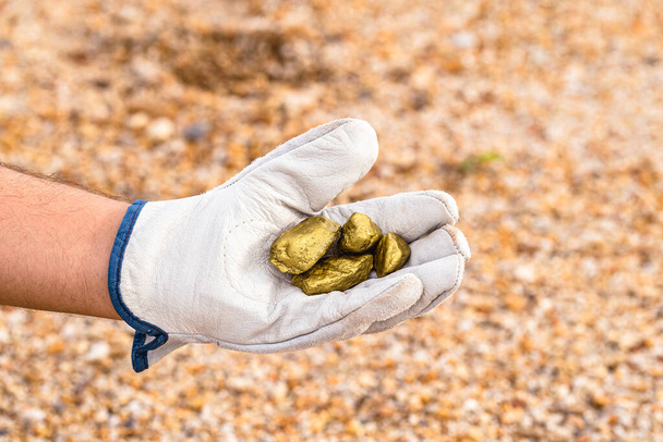 mão mineiro segurando pedras de outro, extração mineral de ouro, conceito de exploração de pedras preciosas
. - Foto, Imagem