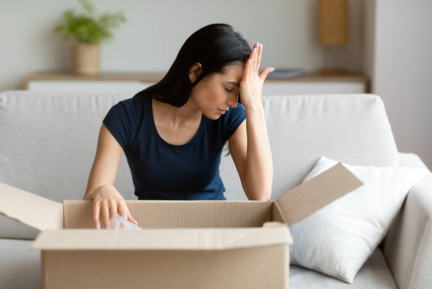 Žena vybalování Chybný balíček Box sedí na pohovce doma - Fotografie, Obrázek