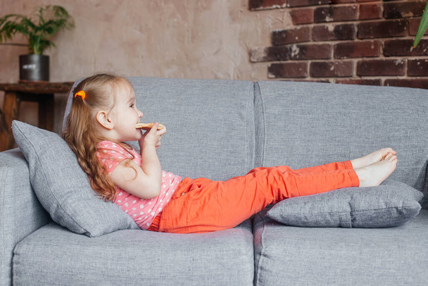 Beautiful little girl eating pizza at home. Fast food concept. - Фото, зображення