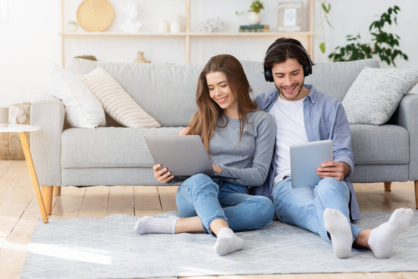 Hombre y mujer usando gadgets mientras pasa el fin de semana en casa
 - Foto, imagen