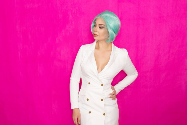 Beautiful young woman with short hair in menthol colors in a white business jacket dress posing against a fuchsia background in studio - Foto, Imagem