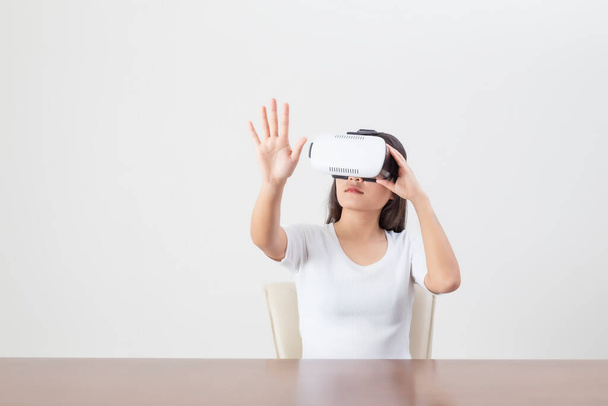 Mujer joven que actúa mientras usa dispositivos VR o gafas de realidad virtual sobre fondo blanco
. - Foto, Imagen