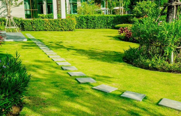 Pathway in de tuin, Groene gazons met stenen paden, Tuin landschap ontwerp, Bochtige loopbrug op groen gras veld en bloementuin, Huis in de tuin, pad in de tuin. - Foto, afbeelding
