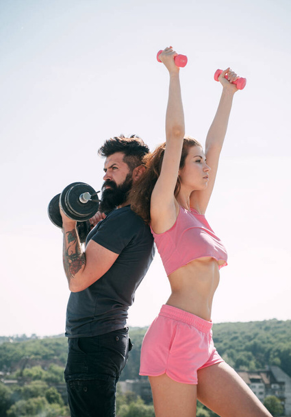 Beautiful brunette woman and bearded handsome man doing sport fitness activities at clear sky background. Attractive young couple do fitness exercises during their leisure time. - Fotoğraf, Görsel