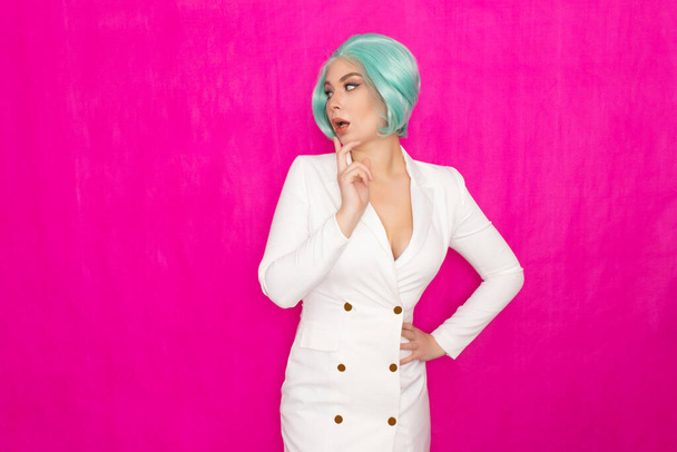 Beautiful young woman with short hair in menthol colors in a white business jacket dress posing against a fuchsia background in studio - Foto, imagen