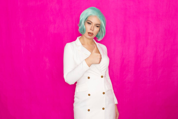 Beautiful young woman with short hair in menthol colors in a white business jacket dress posing against a fuchsia background in studio - Photo, Image